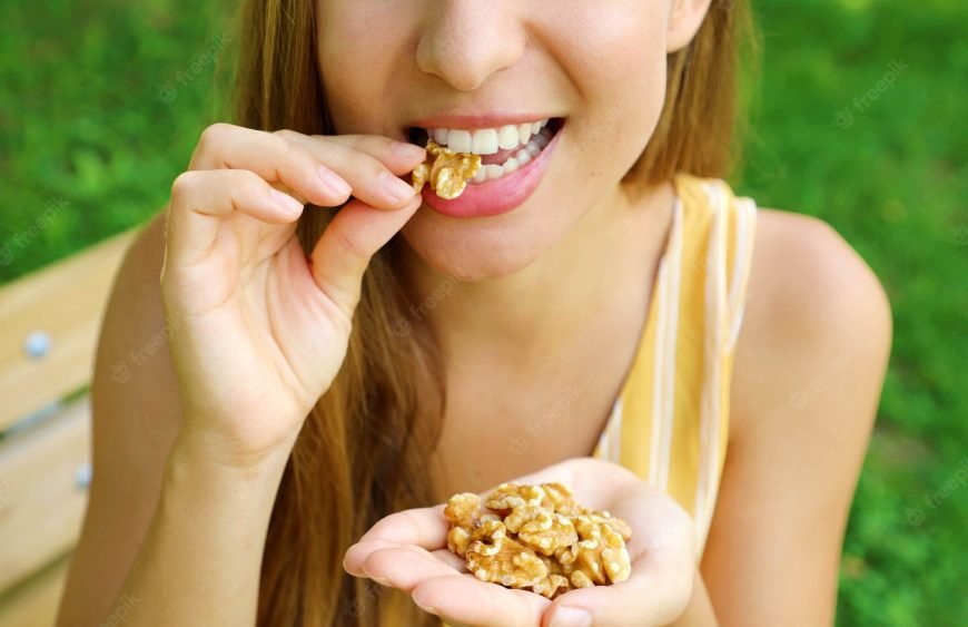 beautiful-smiling-woman-eating-walnuts-park_63239-2630
