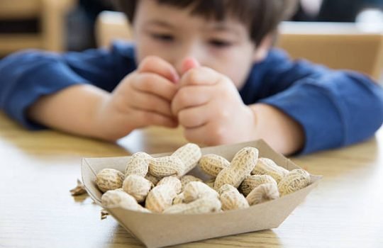 Little boy opening up peanuts to eat in a restaurant